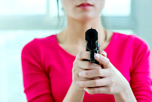 Woman holding a gun indoors.