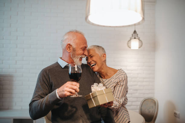 She loves spoiling him A happy senior wife surprising her husband with a birthday present. anniversary gifts stock pictures, royalty-free photos & images