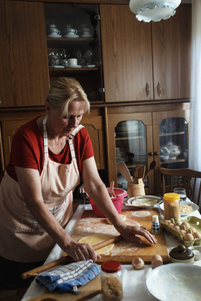 istock Senior female baker kneading dough with rolling pin in kitchen. 862679768