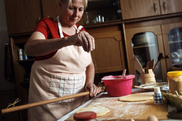 istock Senior female baker kneading dough with rolling pin in kitchen. 862679906