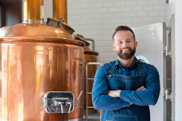 The master brewer in his micro brewery Happy master brewer standing in front of copper vat in his micro brewery, smiling at the camera. microbrewery photos stock pictures, royalty-free photos & images