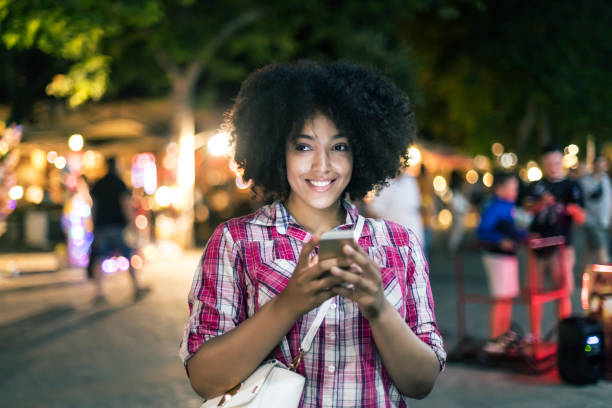 istock Smiling woman using smart phone on street at night 862686368