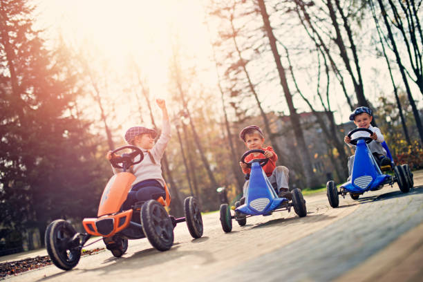 Kids in small cars racing n the park Kids racing in small cars in the park. Little girl is winning. Sunny autumn day.
 kid toy car stock pictures, royalty-free photos & images