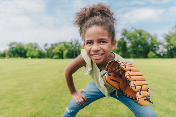 child playing baseball in park portrait of smiling african american little girl with baseball glove playing baseball in park baseball sport photos stock pictures, royalty-free photos & images