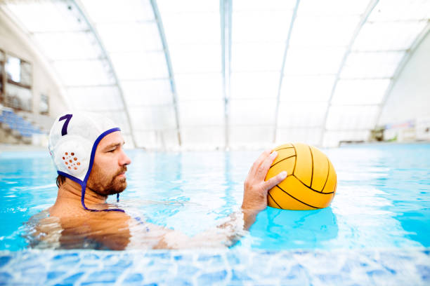Water polo player in a swimming pool. Water polo player in a swimming pool. Man doing sport. water polo cap stock pictures, royalty-free photos & images