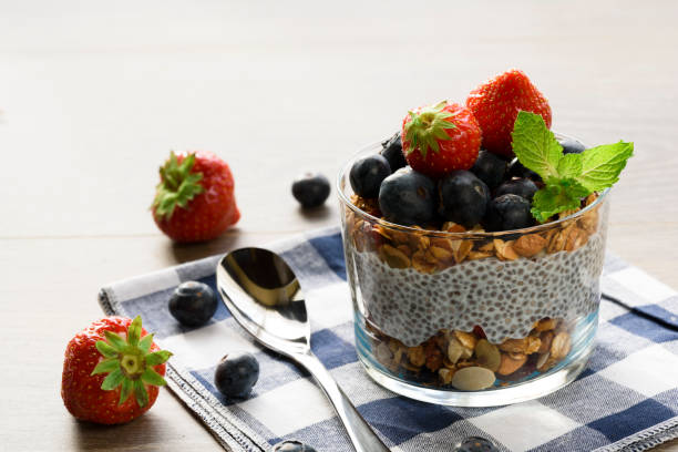 Yogurt with granola, fresh blueberries, chia seeds and oats in a glass over wood background. close up