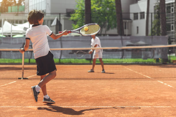 criança do sexo masculino jogando tênis com o adversário - tennis court sport net - fotografias e filmes do acervo