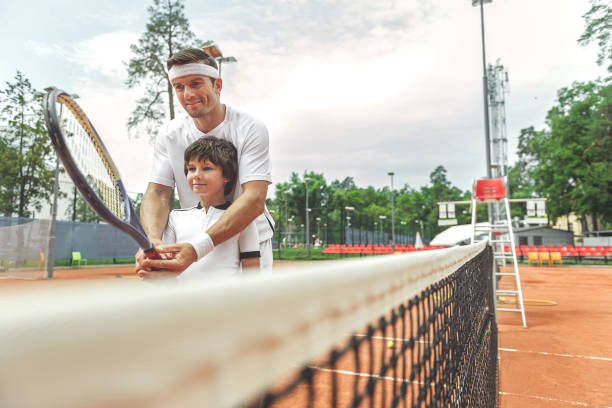 istock Interested father teaching son to play tennis 862704330