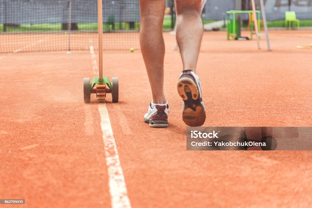 Busy male working on court Man is painting necessary lines at tennis field. Close up of male legs. Copy space Painting - Activity Stock Photo