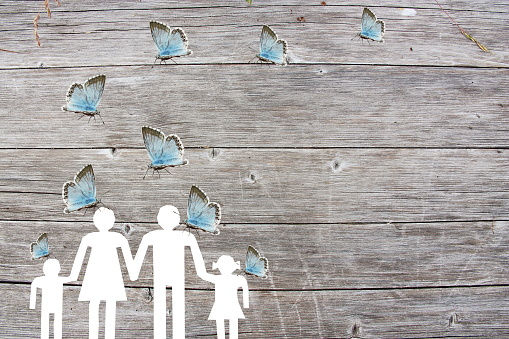 Family on a wooden background with blue butterflies welfare concept