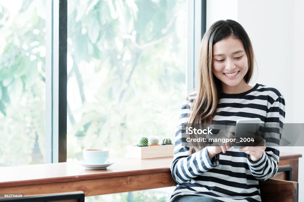 Jeune femme asiatique à l’aide de téléphone intelligent assis par café fond de la fenêtre, personnes technologie et style de vie - Photo de Femmes libre de droits