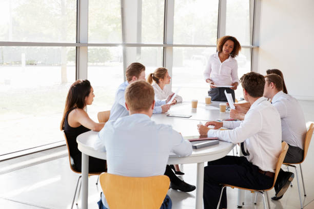 istock Businesswoman stands holding documents at a team meeting 862717432