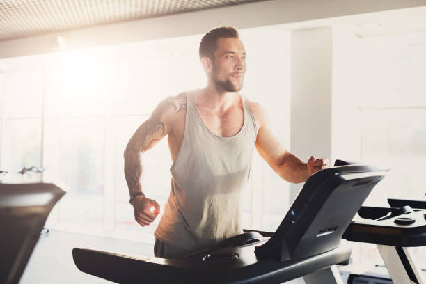 istock Young man in gym run on treadmill 862720796