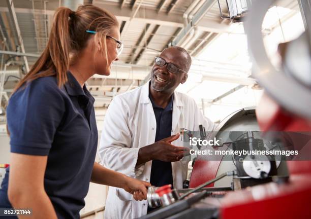 Engineer Talking To Female Apprentice By Machinery Close Up Stock Photo - Download Image Now
