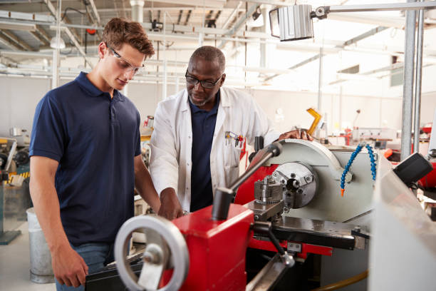 istock Engineer showing male apprentice how to operate machinery, close up 862721148