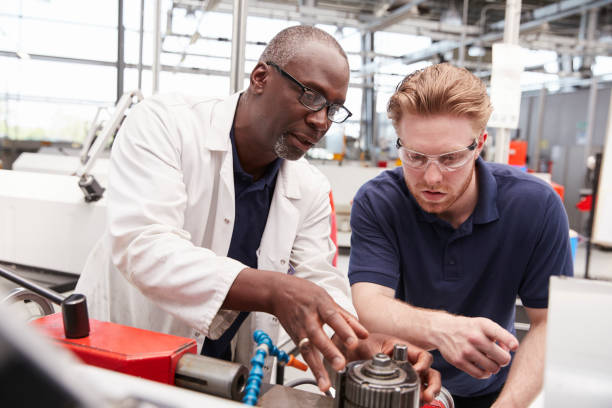 istock Engineer advising a male apprentice in a factory, close up 862721422