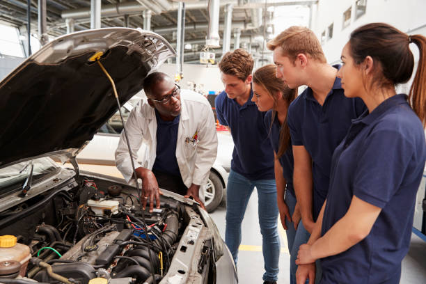 istock Mechanic instructing trainees around the engine of a car 862721716