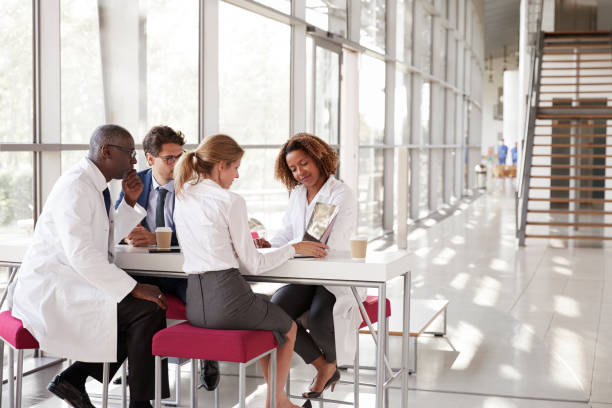 istock Four doctors looking at laptop in a modern hospital lobby 862721718