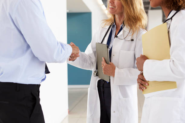 istock Three male and female doctors shaking hands, mid section 862724432