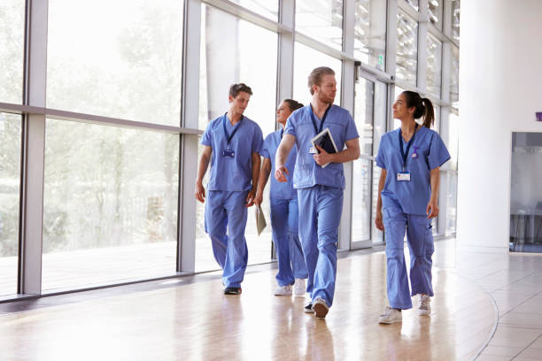 quattro operatori sanitari in scrub che camminano nel corridoio - paramedico foto e immagini stock