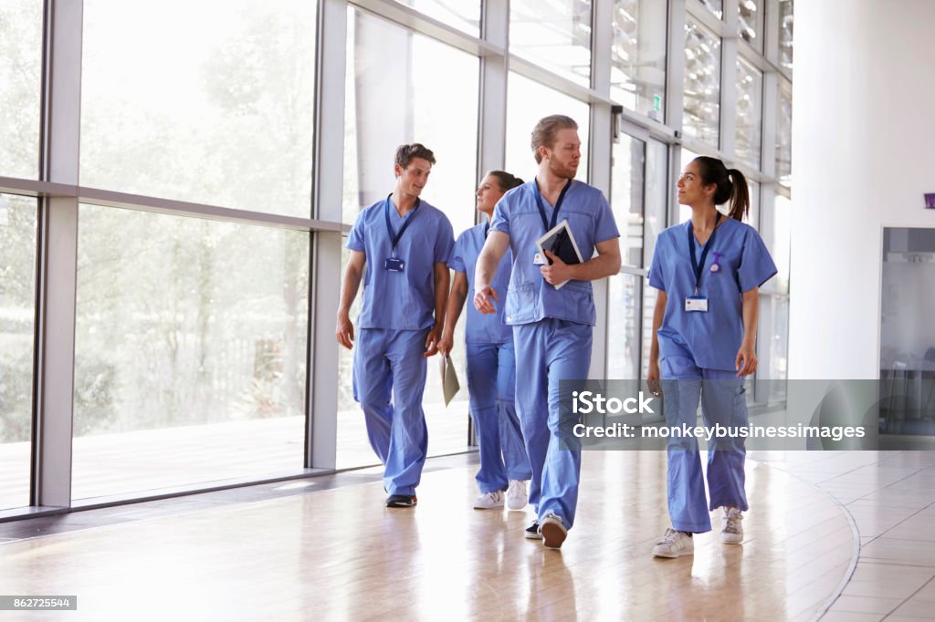 Four healthcare workers in scrubs walking in corridor Nurse Stock Photo