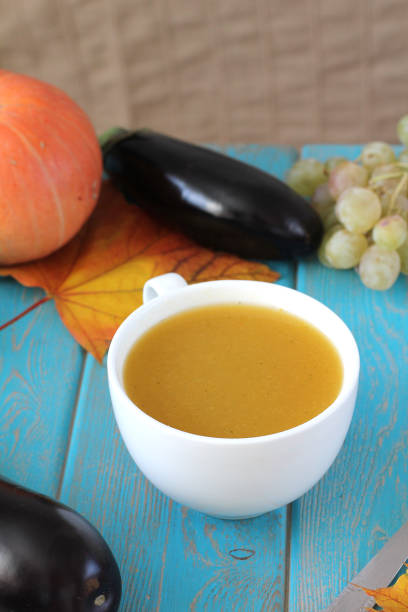Pumpkin soup in white mug on blue table. Harvest composition.