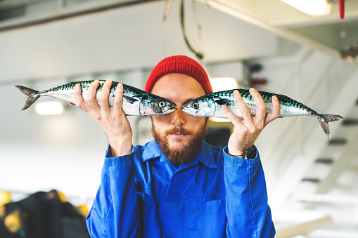 Pescador con pescado fresco en la cubierta del barco de pesca photo