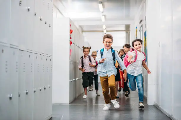 cute funny pupils running through school corridor