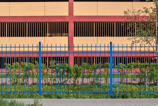 Blue fence on a background of pink walls multilevel parking lot in St. Petersburg in a sunny day.