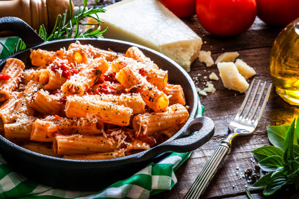 pasta en una sartén de hierro fundido tirado en mesa de madera rústica - italian cuisine fotografías e imágenes de stock