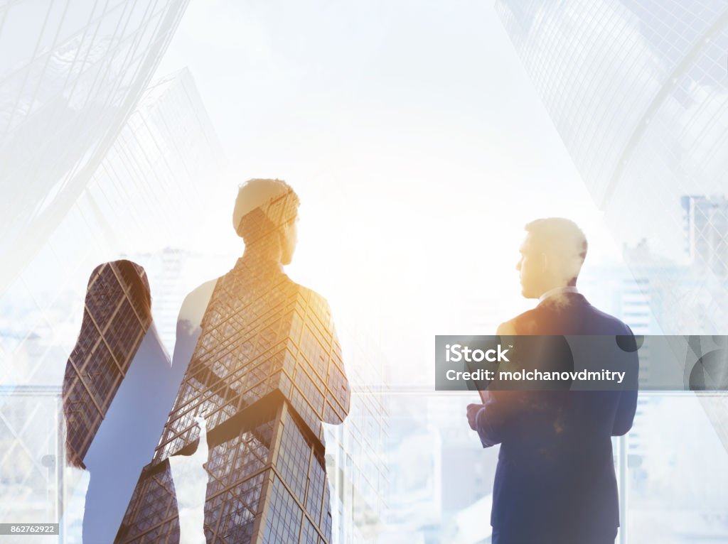 Abstract business concept three silhouettes businessmen Abstract business concept with three silhouettes of businessmen double exposed on modern skyscrapers backdrop. Lawyer Stock Photo