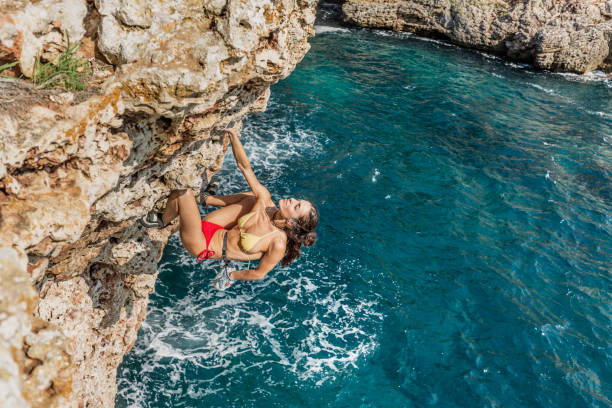 woman practicing psicobloc rock climbing in minorca spain - climbing men sea cliff imagens e fotografias de stock