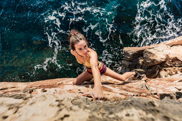 woman practicing psicobloc rock climbing - climbing men sea cliff imagens e fotografias de stock