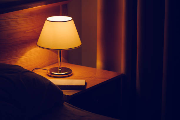 elektrische lampe und buch am krankenbett - schwache beleuchtung stock-fotos und bilder