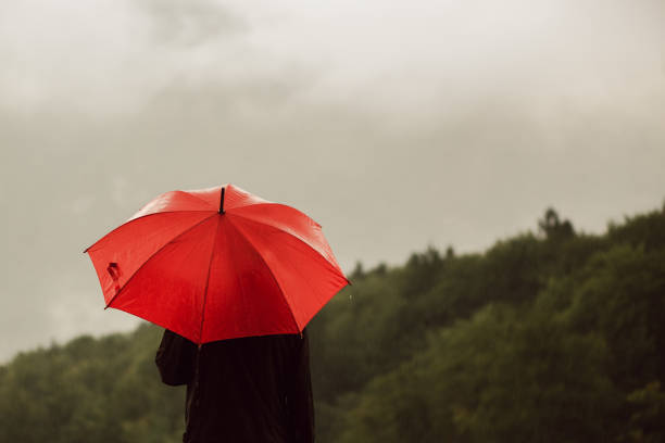 雨の中で孤独に立っている赤い傘を持つ男 - rain drenched one person standing ストックフォトと画像