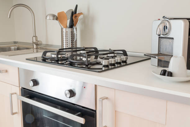 istock New kitchen. Counter top with assorted utensils, a sink,  kitchen gas stoves, coffee capsules, white coffee cup and coffee maker 862789682