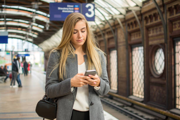 istock Young woman using phone at train station. 862801360