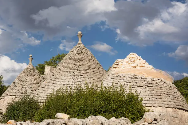 Old trulli of which one collapsed and cloudy sky