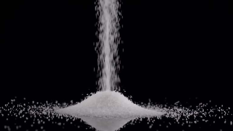 White sugar poured on black background