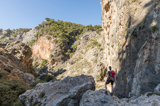A female hiker is overlooking from a boulder the scenic Aradena Gorge in the southwestern part of Crete.\n