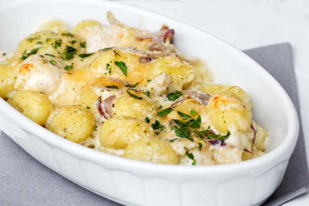 Serving of red onion and chicken gnocchi in white ceramic dish.