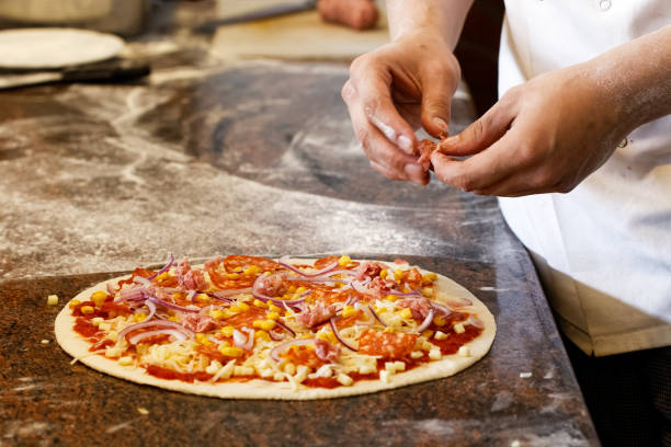 istock Cook's hands putting salsiccia sausage  on tomato base pizza. 862994800