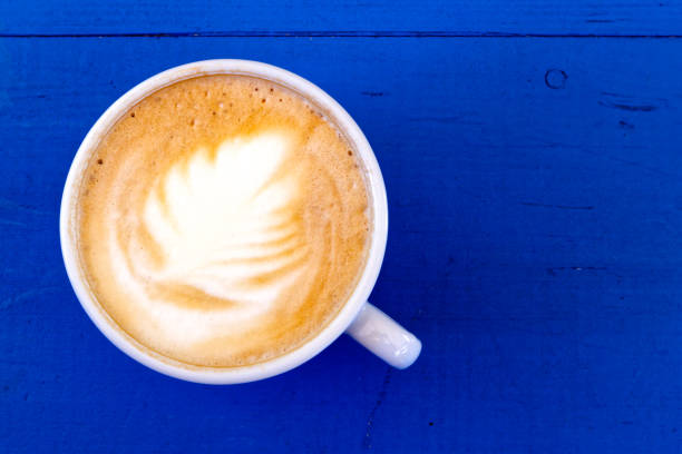 istock Cappuccino in white ceramic cup on blue painted wood from above. 863092922