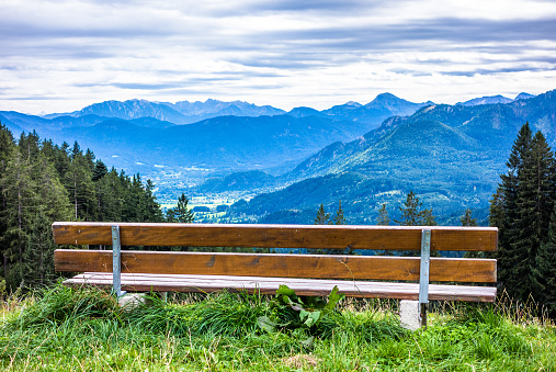 An empty bench in the Dolomites, Italy. Mountain range in the background.