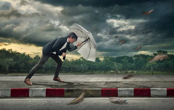 Photo of Businessman with white umbrella protecting himself from the storm.  Business heavy tasks and problems concept.