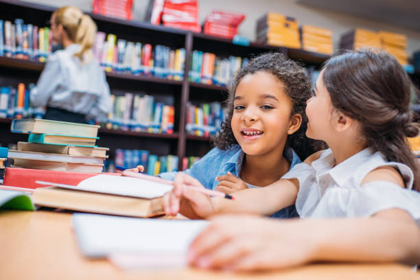 istock schoolgirls gossiping at library 863109414