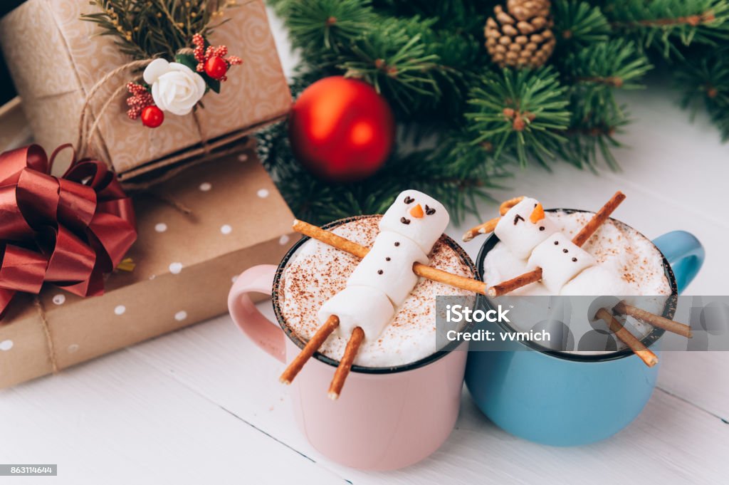 a mug with hot chocolate on a wooden table with a marshmallow man who is resting in a mug Christmas Stock Photo