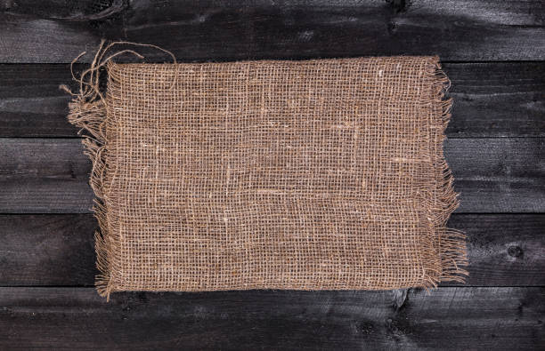 istock Burlap on black wooden background, top view 863124230
