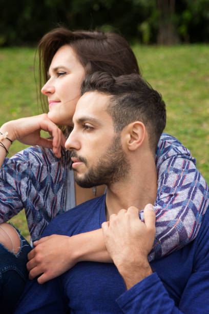 istock young beautiful couple sitting outside in Park 863124312