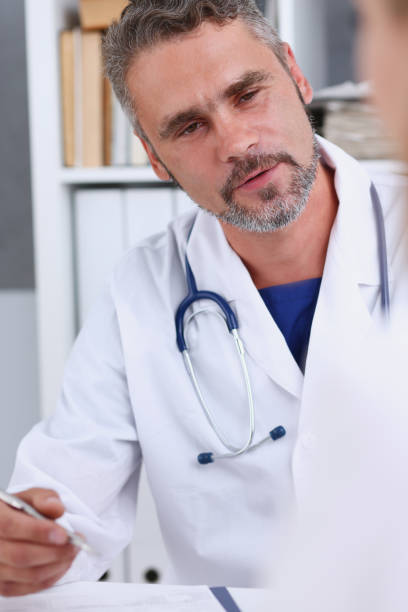 istock Smiling handsome mature doctor communicate with patient 863133358